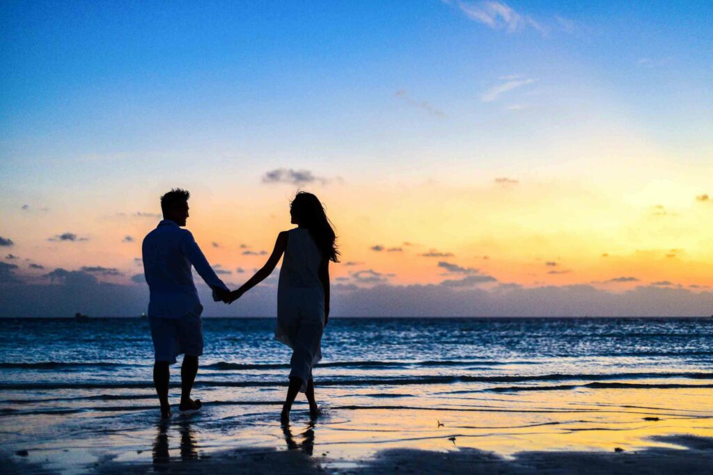 pexels photo 1024960 1024960 A romantic couple walks hand in hand on a tropical beach at sunset, enjoying a serene moment together.