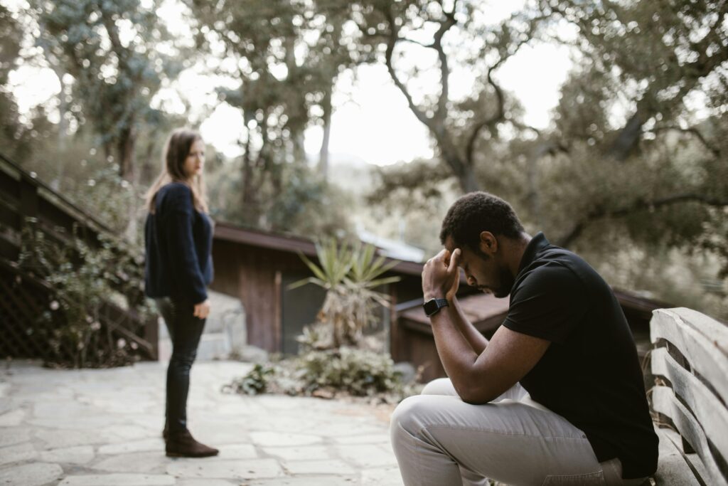 pexels photo 6670211 6670211 A couple in a tense moment, outdoors on a bench, focusing on emotional distress.